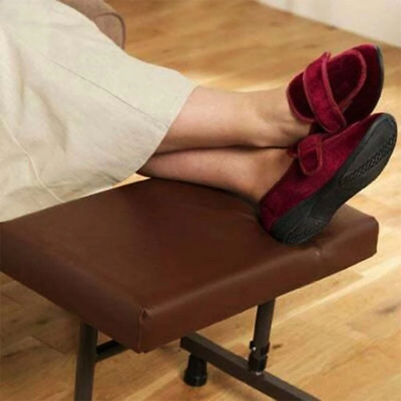 Person resting feet on a brown adjustable leg rest stool.