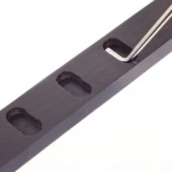 Close-up of a metal adjustment tool in a wooden bar with slots.