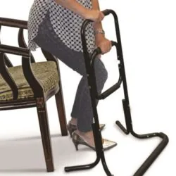 Person using a black standing aid next to a chair.