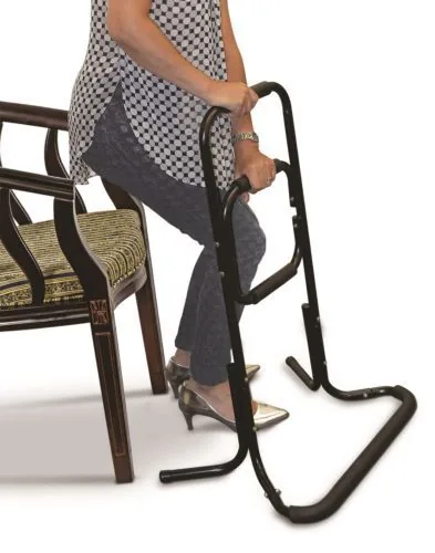 Person using a black standing aid next to a chair.