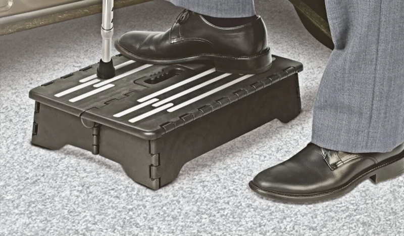 Person using a black folding step stool to step into a vehicle.