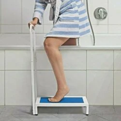 Person using a non slip bath step with a handle to step into a bathtub.