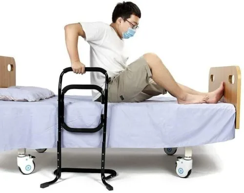 Person using a black standing aid on a bed.