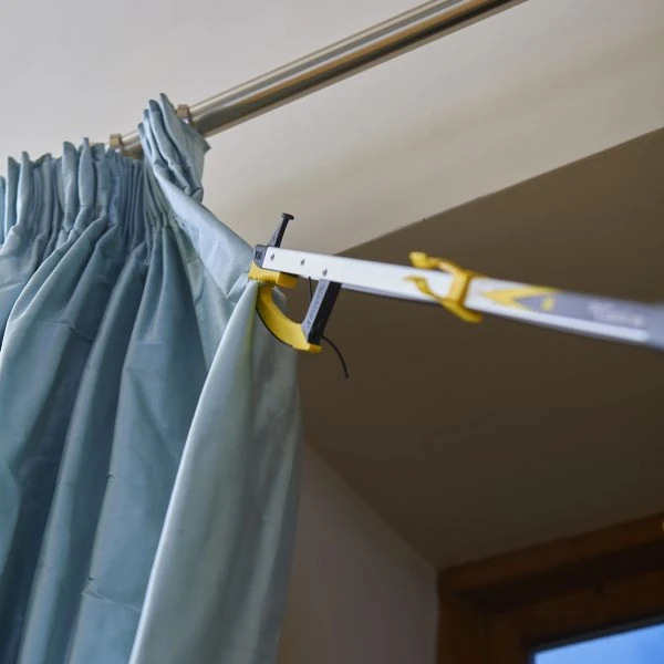 Reacher grabber holding a curtain on a rod.