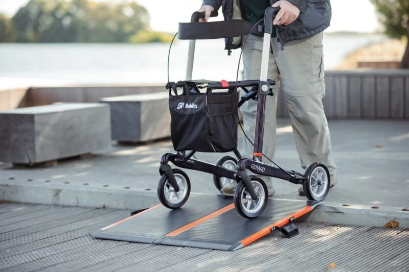 Person using a Gepard rollator on a ramp in an outdoor setting.