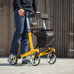 Person using a yellow Gepard rollator outdoors.