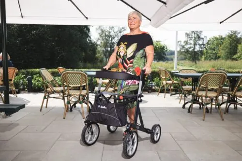 Person using Mobilex Lion rollator with large wheels on a patio.