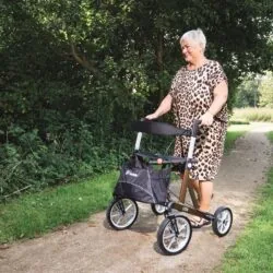 Person using a Mobilex Lion rollator on a gravel path surrounded by greenery.