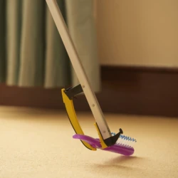 Reacher grabber stick picking up a purple comb from the floor.