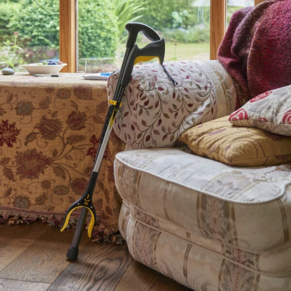 Arthri-Grip PRO Reacher leaning on a sofa in a cozy living room.