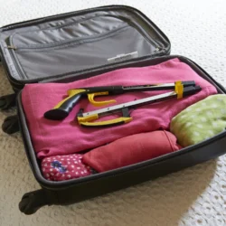 Folding picker reacher placed inside an open suitcase with clothes.