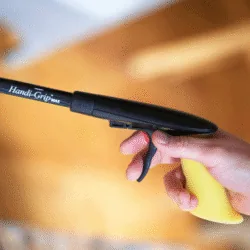 Person holding a Handi-Grip MAX reacher with a yellow handle.
