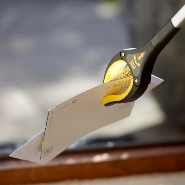 Handi-Grip Mini Grabber Tool holding an envelope.