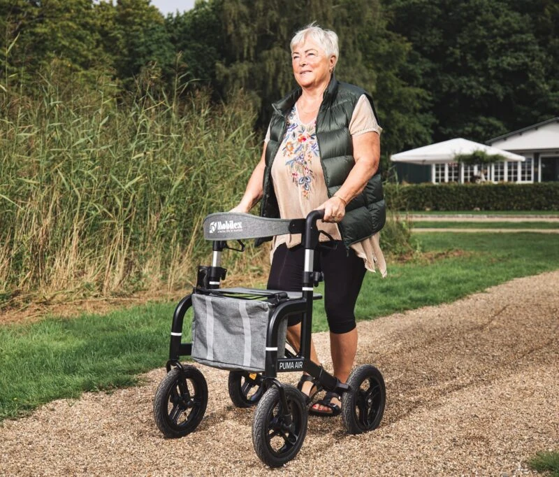 Person using the Mobilex Puma Air rollator on a gravel path.