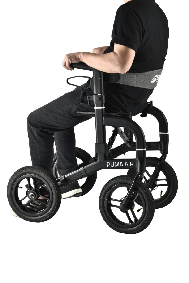 Person seated on a Mobilex Puma Air rollator with large wheels.