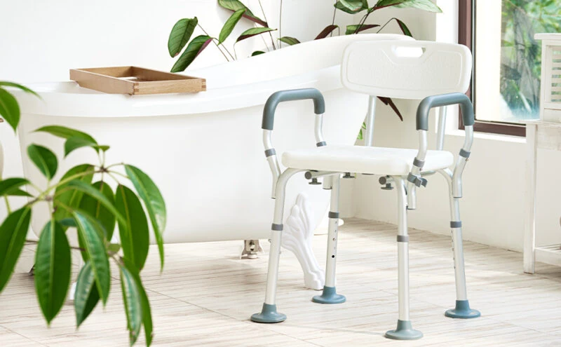 Shower chair with arms and adjustable legs in a bathroom setting.