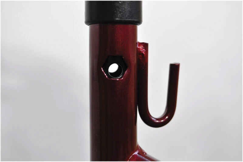 Close-up of a red metal frame with a hook and hole.