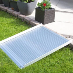 Aluminum rollable ramp placed over a grass and stone step.