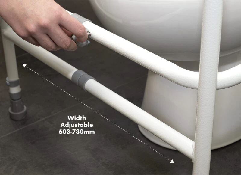 Hand adjusting the width of a toilet support frame next to a toilet.