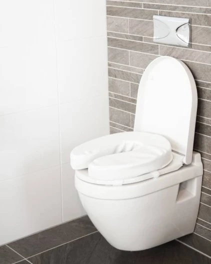 Padded raised toilet seat installed on a white toilet in a modern bathroom.