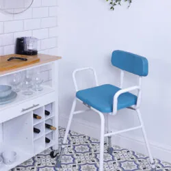 Height adjustable perching stool with padded seat and backrest in a kitchen setting.
