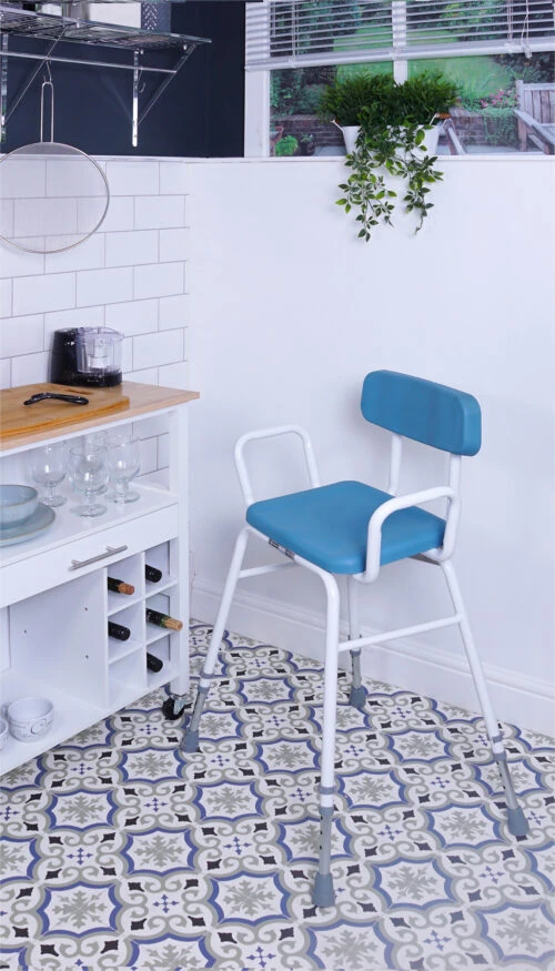 Height adjustable perching stool with padded seat and backrest in a kitchen setting.