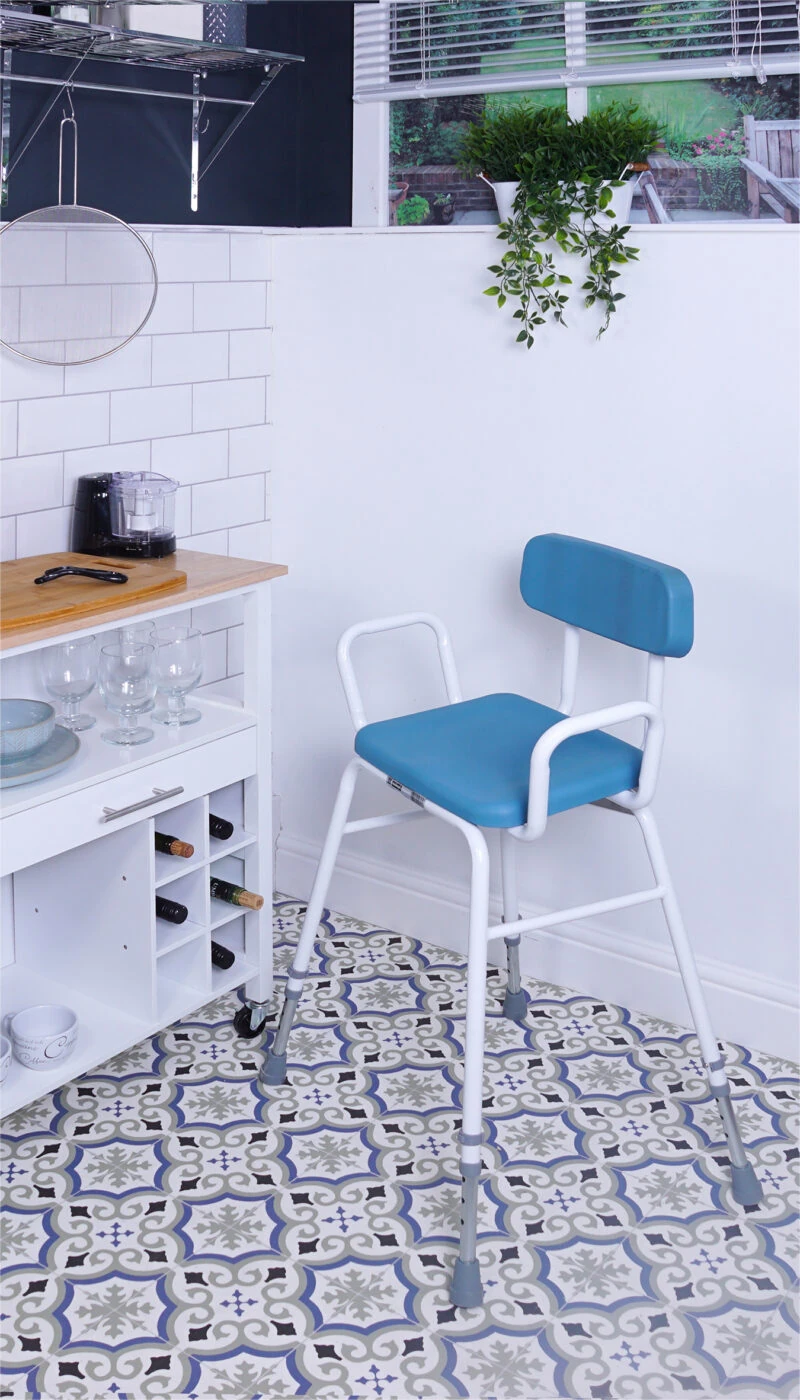 Height adjustable perching stool with padded seat and backrest in a kitchen setting.