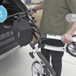 Person loading a folded Trust Rollator into a car trunk.