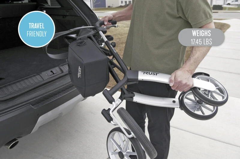 Person loading a folded Trust Rollator into a car trunk.