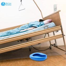 Hospital bed with a patient and a blue bedpan on the floor.