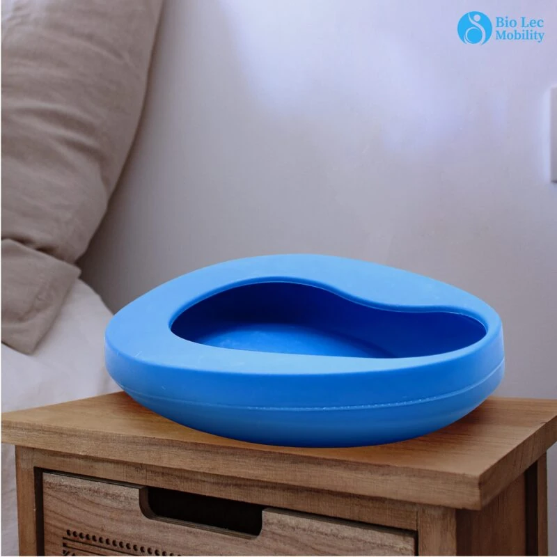 Blue bedpan on a wooden nightstand beside a bed.