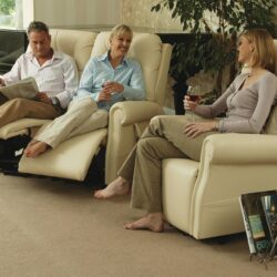 Three people relaxing on cream recliner chairs in a living room.