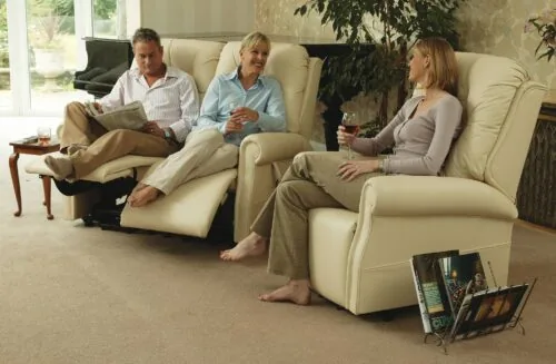 Three people relaxing on cream recliner chairs in a living room.