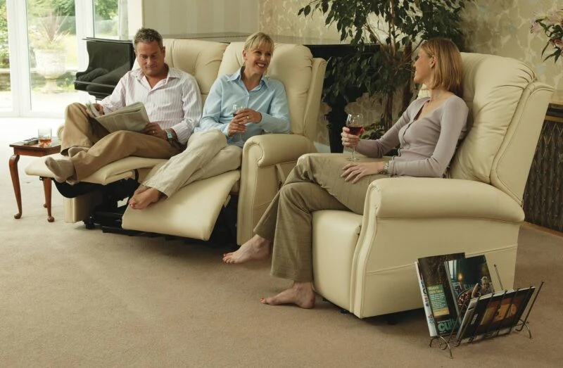 Three people relaxing on cream recliner chairs in a living room.