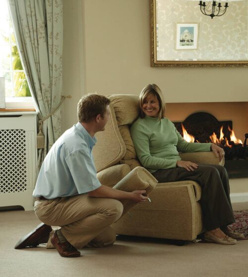 Woman sitting in a recliner near a fireplace, with a man kneeling beside her.