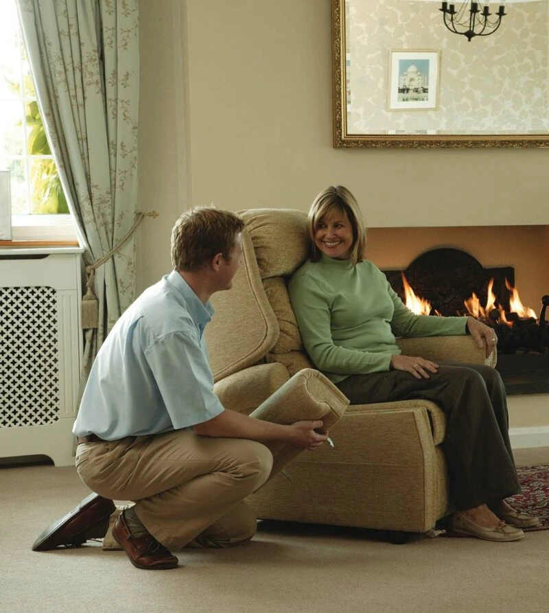 Woman sitting in a recliner near a fireplace, with a man kneeling beside her.
