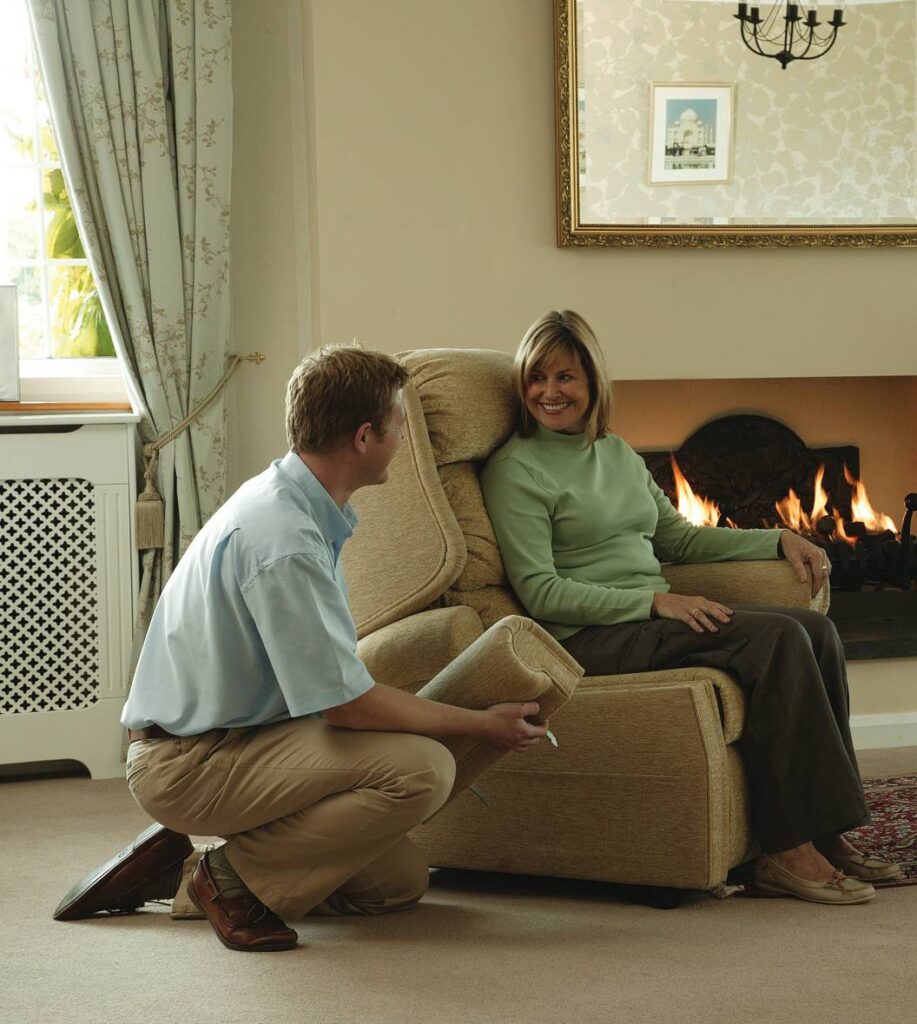 Woman sitting in a recliner near a fireplace, with a man kneeling beside her.