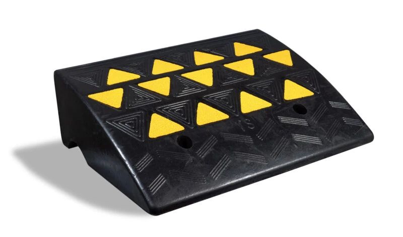 Black rubber kerb ramp with yellow reflective triangles.