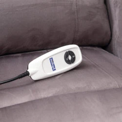Remote control on a grey recliner chair seat.