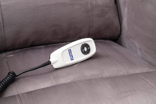 Remote control on a grey recliner chair seat.