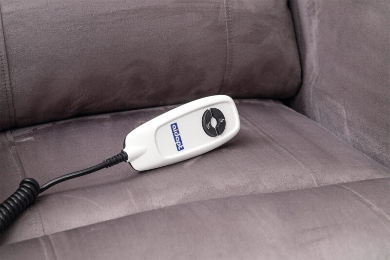 Remote control on a grey recliner chair seat.