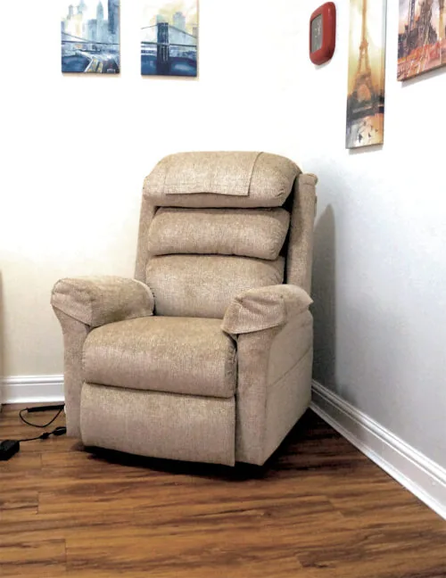Beige riser recliner armchair in a room with wall art.