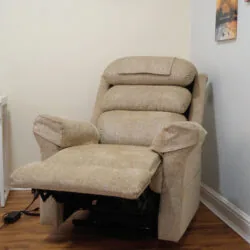 Beige riser recliner armchair with extended footrest in a room.
