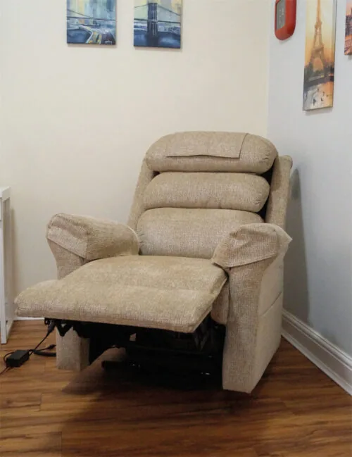 Beige riser recliner armchair with extended footrest in a room.
