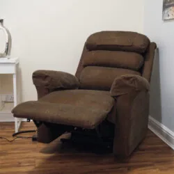 Brown riser recliner armchair with extended footrest in a room.