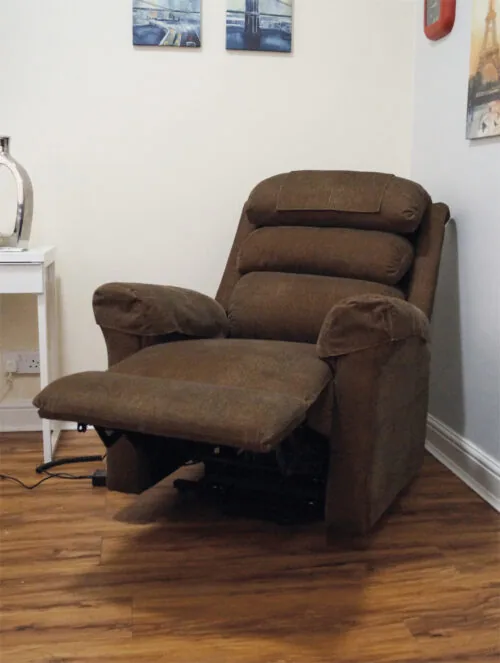 Brown riser recliner armchair with extended footrest in a room.