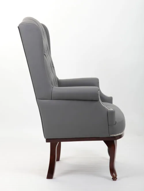 Side view of a grey high back armchair with dark mahogany legs.