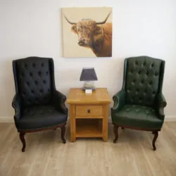 Two high back armchairs, one black and one green, flanking a wooden side table.