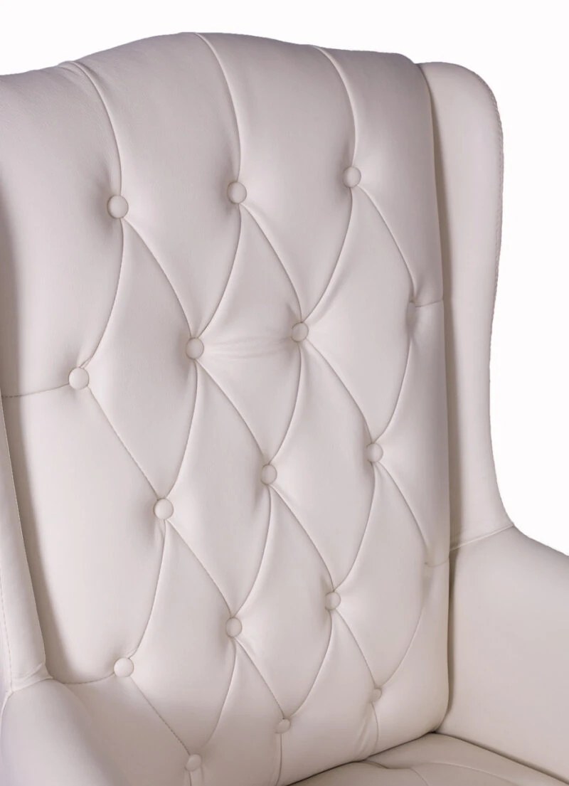 Close-up of a cream tufted armchair backrest.