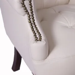 Close-up of cream armchair with studded armrest and dark wooden legs.